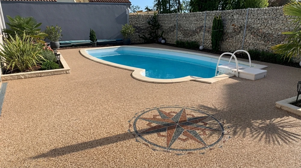 Terrasse extérieure en résine de marbre couleur sable entourant une piscine coque polyester en forme haricot aux eaux turquoise