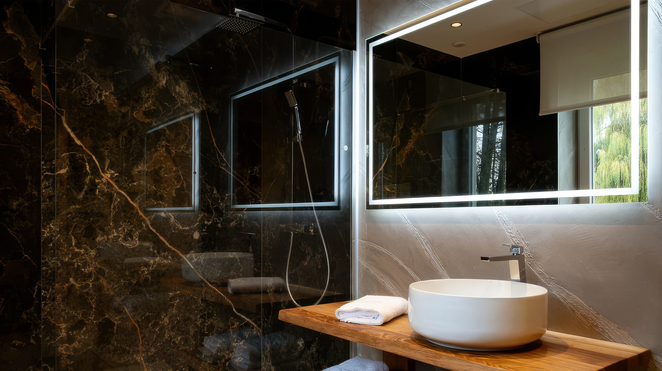 Salle de bain moderne avec baignoire blanche au premier plan, vasque suspendue avec meuble en bois clair, WC suspendu et sèche-serviettes chromé