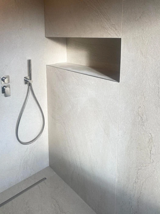 Salle de bain luxueuse avec murs en marbre blanc veiné, douche à l'italienne habillée de marbre noir Marquina, baignoire îlot blanche autoportante