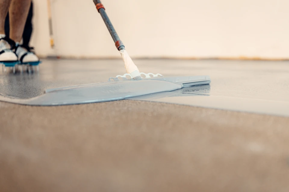 Garage résidentiel moderne avec sol en résine époxy gris moucheté, murs blancs et plafond avec poutres apparentes