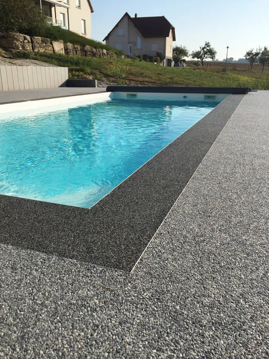 Sol en résine époxy avec granulats décoratifs type flocons vinyle (flakes), finition mate texturée, coloris gris anthracite moucheté blanc