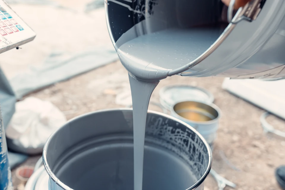 Personne appliquant un revêtement époxy sur sol intérieur avec rouleau à picots métalliques